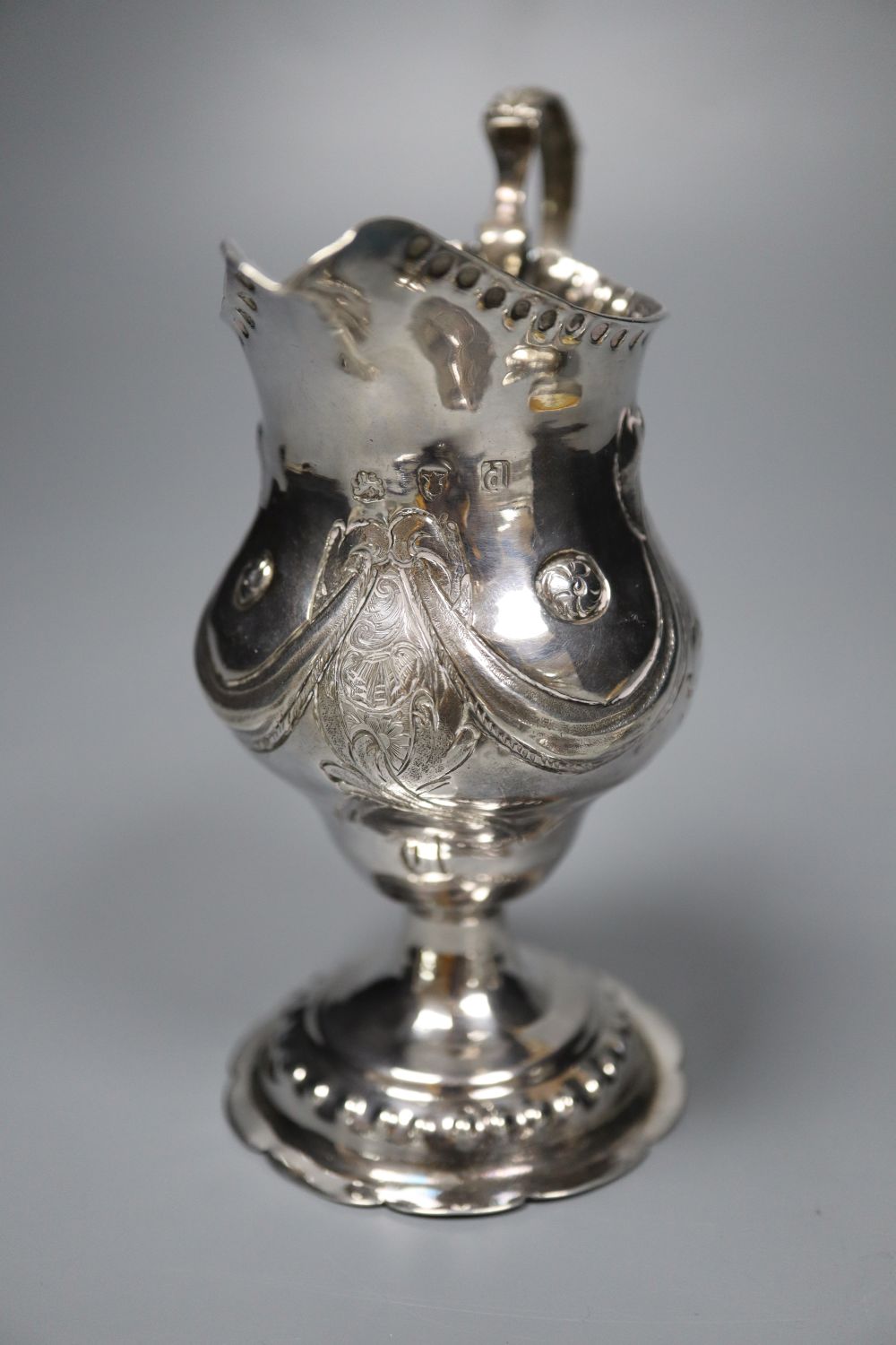 A George III silver inverted pear shaped cream jug, London, 1779 and a George III silver globe shaped pedestal pepperette